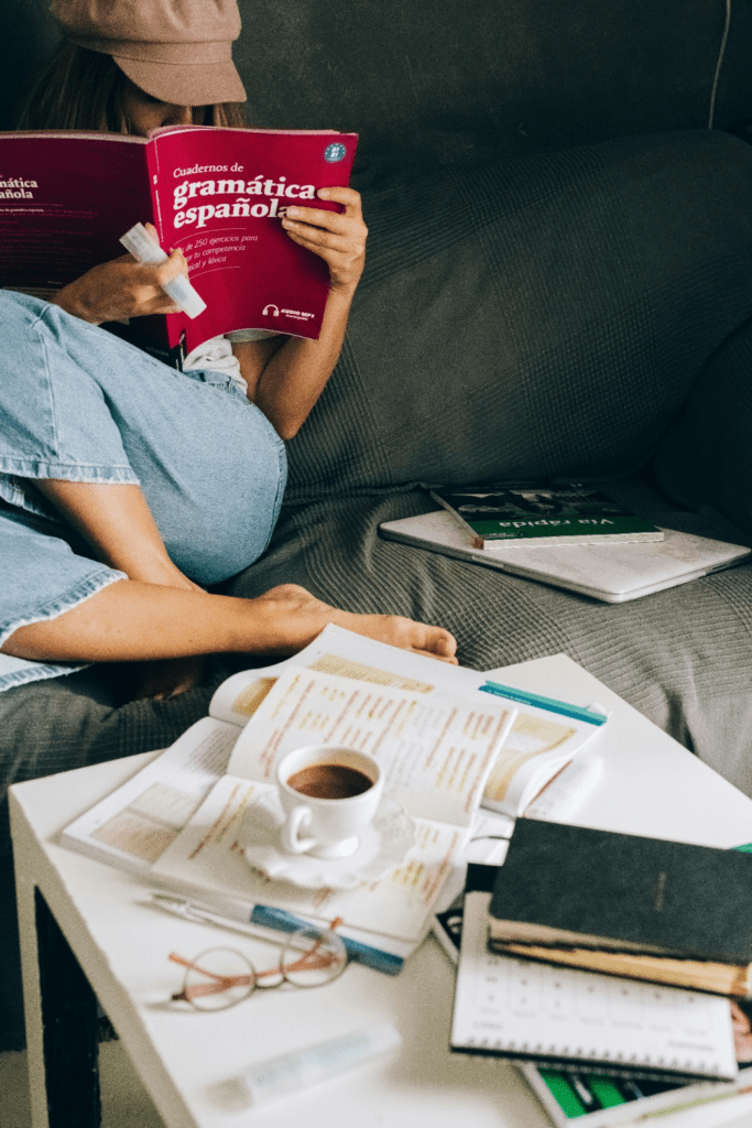 A woman sitting on the couch while reading a book