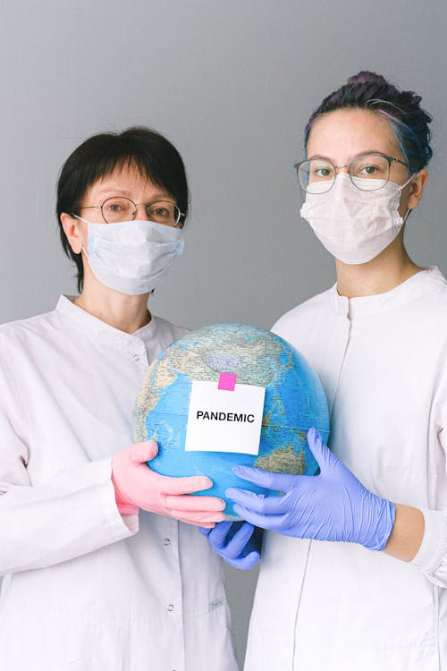 people with face masks and latex gloves holding a globe