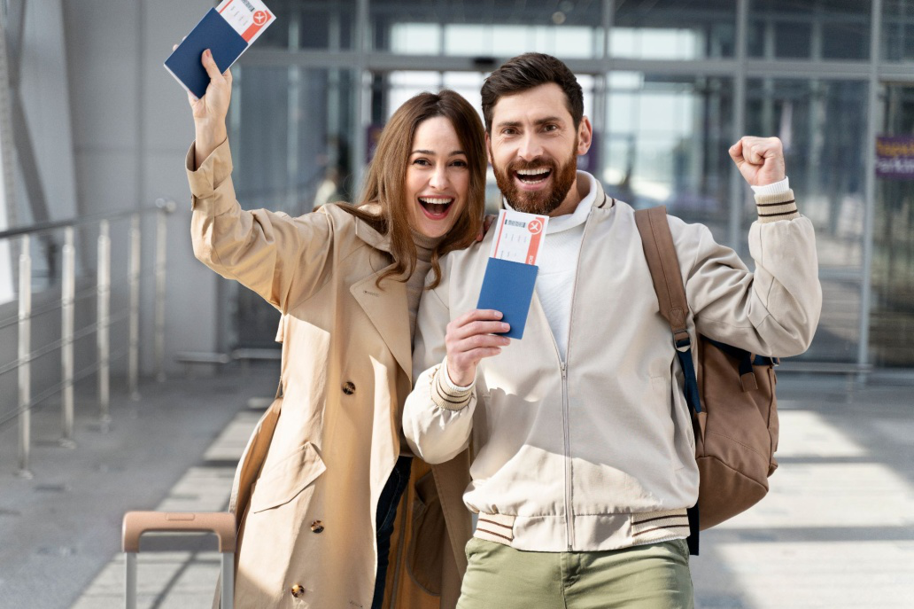 Smiling couple holding passports and approved visas, standing together with travel documents in hand.