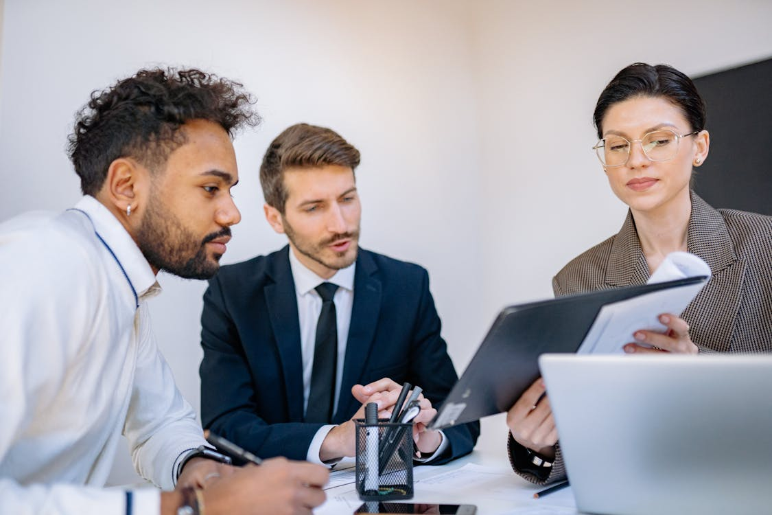 Coworkers examining a document during a meeting focused on English-to-Spanish document translation for USCIS.