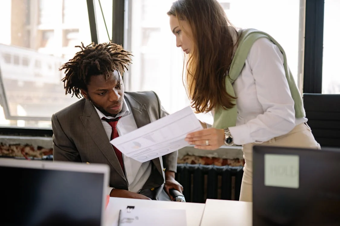 A man and a woman discussing documents related to English-to-Spanish USCIS translation requirements.