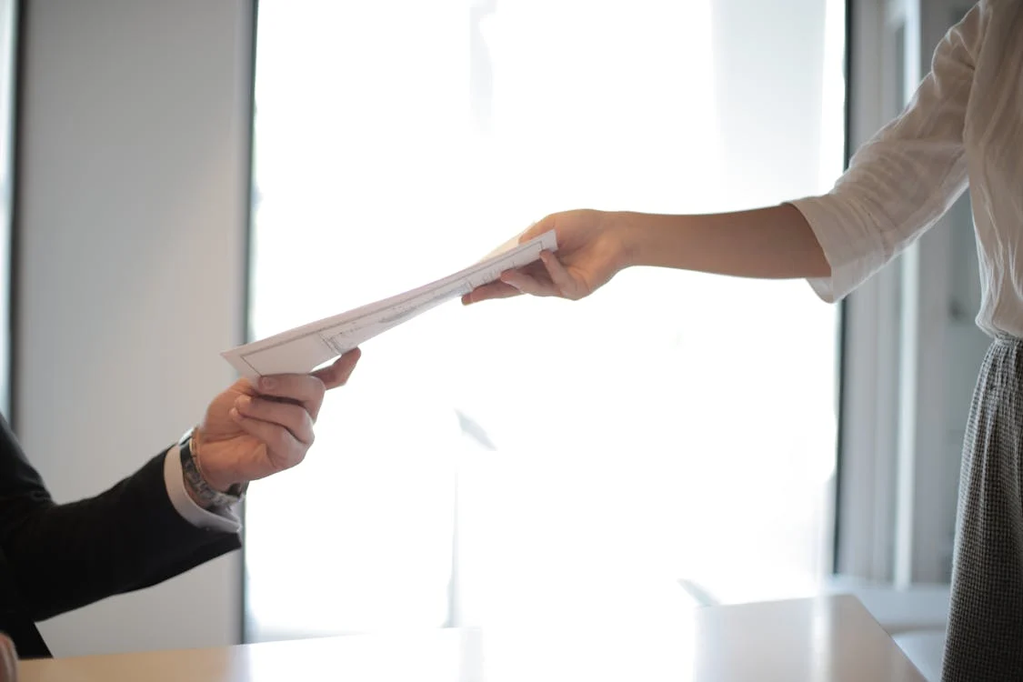 A person hands over a birth certificate.
