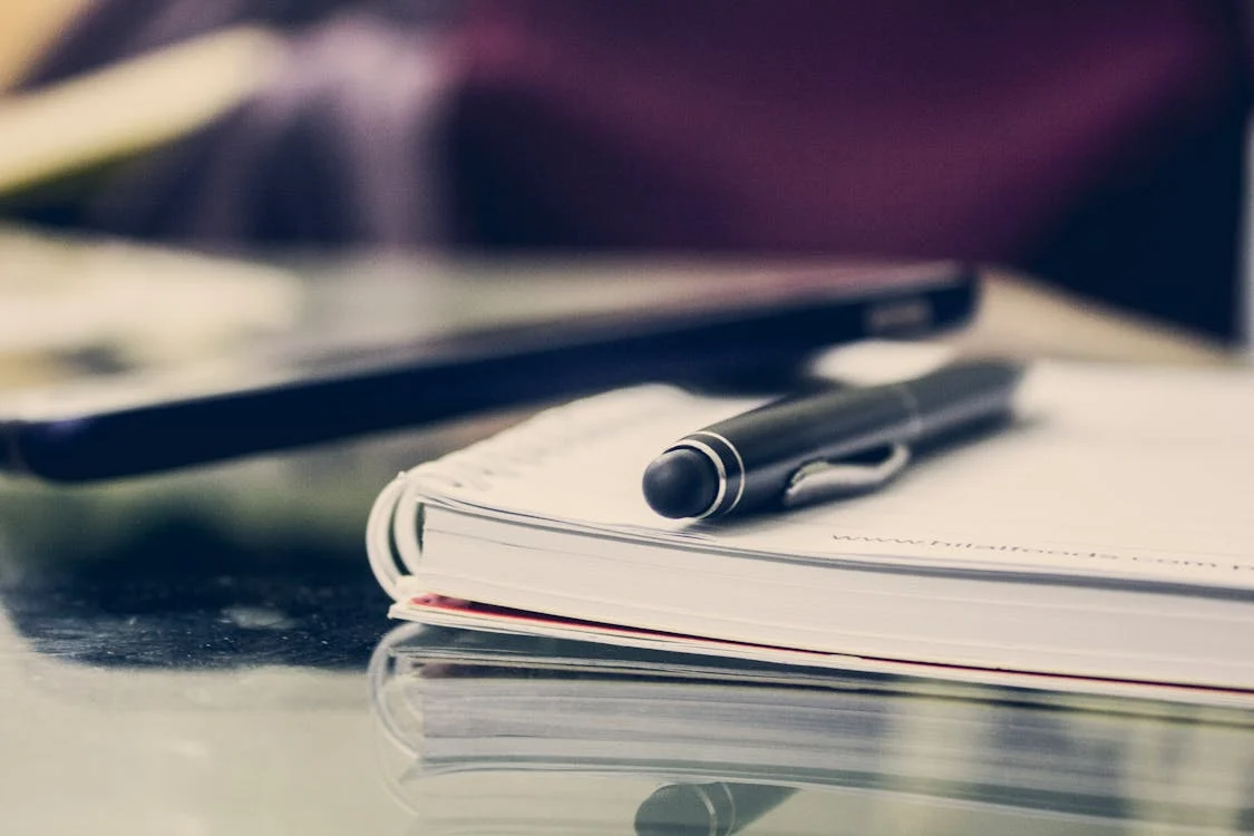 a notebook and a pen on a desk.