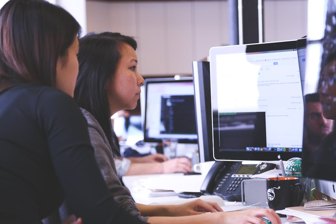 two women sitting and looking at a computer screen