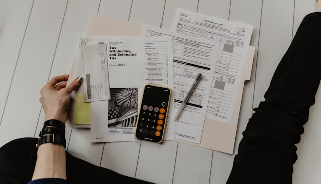 This photo shows Hands working on documents, phone and reports