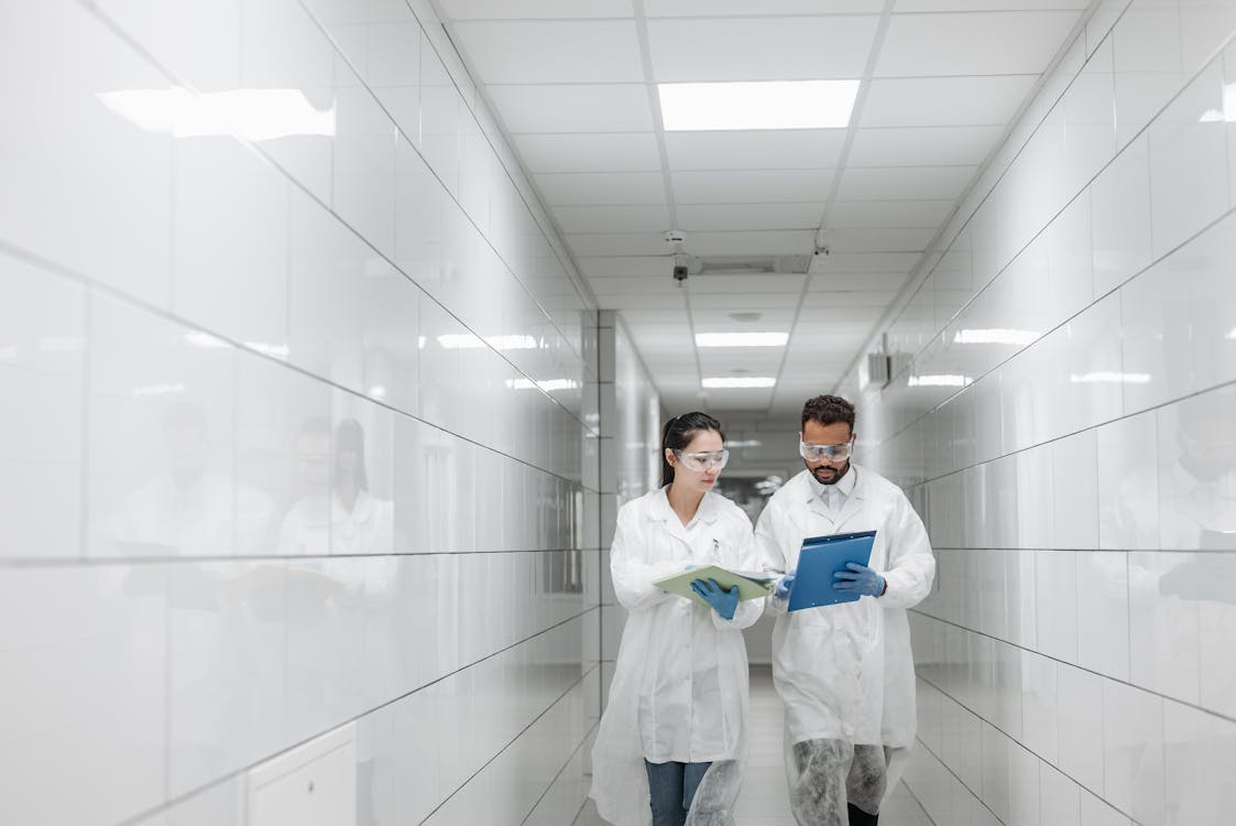 Medical professional wearing personal protective equipment walking in a hallway while reviewing a translated clinical trial document