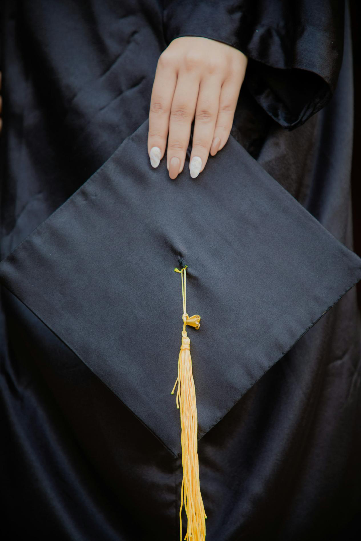 Graduate in a gown holding a graduation cap