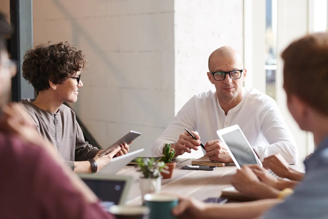 A group of coworkers talking at a desk