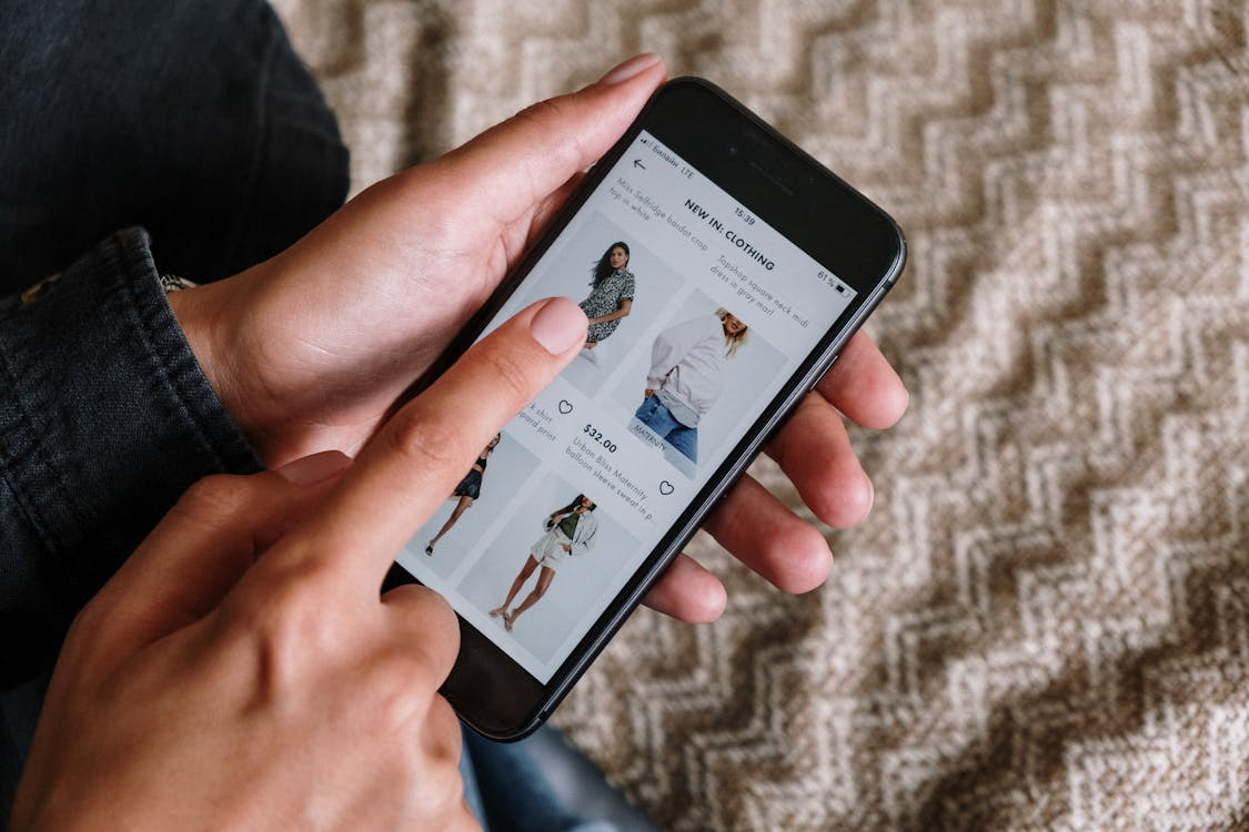 Person holding a smartphone with an online clothes store displayed