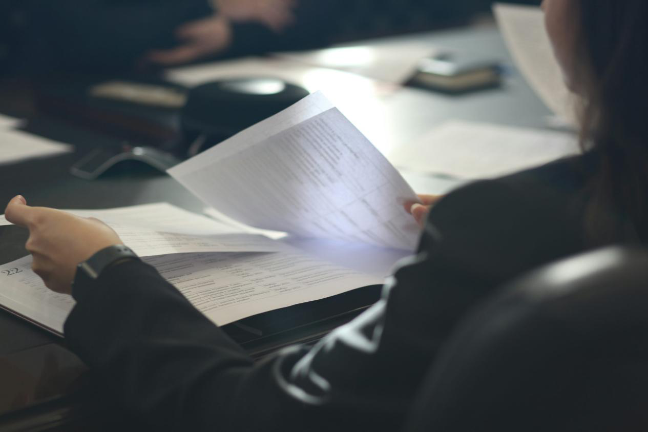 A woman sitting at a table reading paperwork