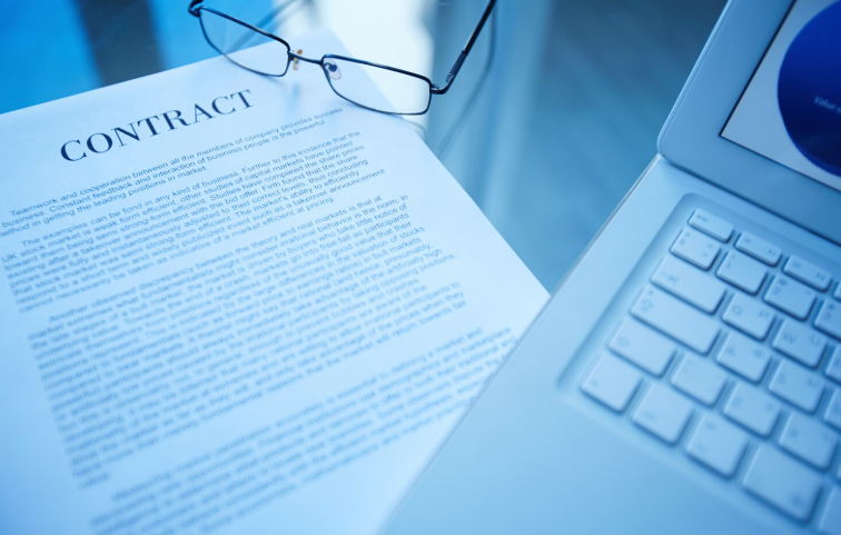  glasses placed on contract document beside laptop in office workspace