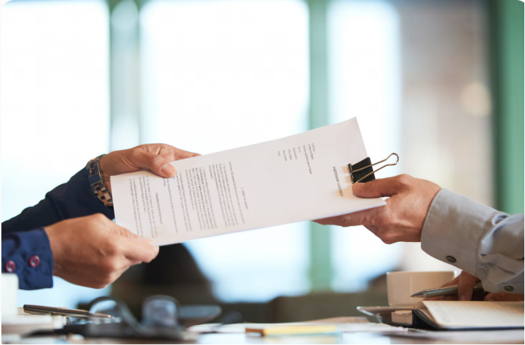 two professionals passing signed contract documents during business deal